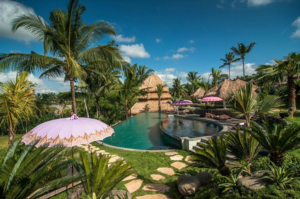 Featured image for 4-day intensive yoga retreat in Ubud, Bali with breathtaking image of Blue Karma Retreat Resort showing poolside view, bamboo built structures, a pink umbrella, lush green landscape and more