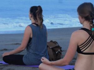 Featured image for 4-day surf camp and yoga retreat for 2017 in Bali, Indonesia with two female yogis sitting in lotus pose on the Bali beach
