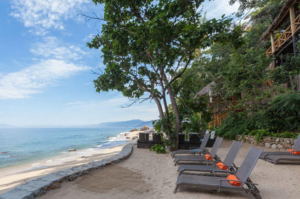 Featured image of top 30 yoga retreats for November 2017 with 7-Day Exclusive Yoga Retreat in Puerto Vallarta, Mexico displaying beachside view with patio chairs and a crystal clear blue sky