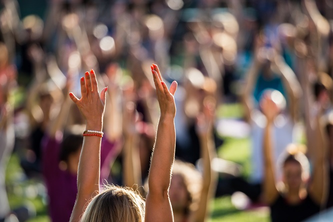 Outdoor image of yoga instructors and students with hands in the air for a yoga teacher training in California